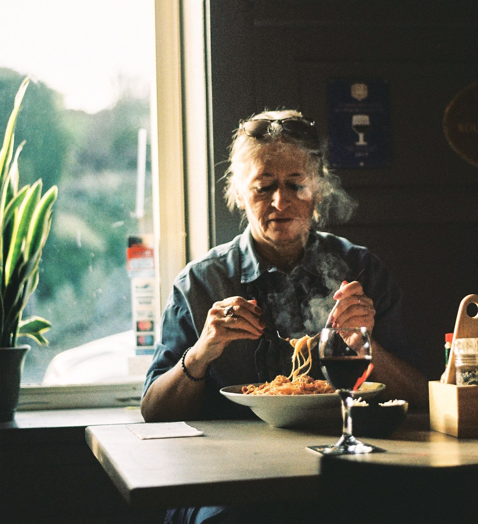 Gast geniet van een dampend bord spaghetti aan het raam